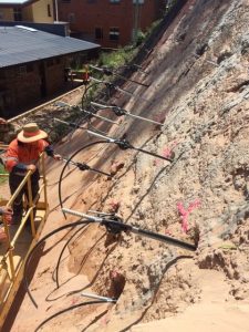 Anchors and grout lines are installed horizontally in earth wall, ready for grout to be pumped in.