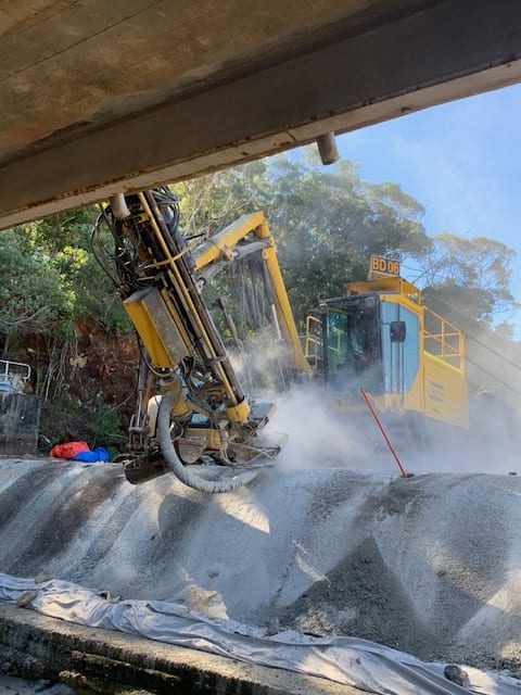 Dust fills the air as a drill rig bores into the ground on site at Paluma Dam.