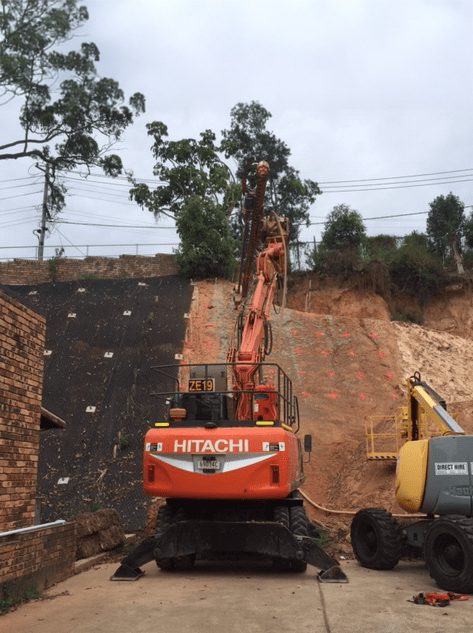 Photo of Orange Hitachi drill rig from behind as it drills into earth horizontally