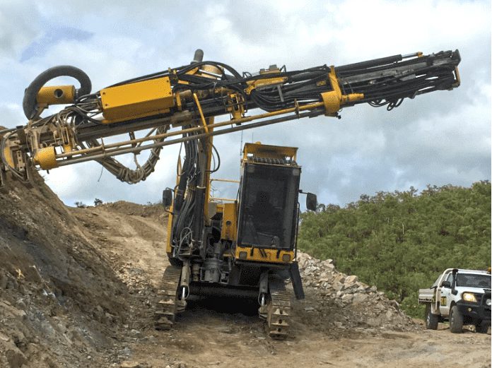 Drill rig performing rock bolting services on a rock wall face, installing bolts (anchors) to strengthen the wall and prevent rockfall.