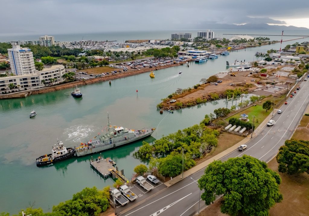 The HMAS Townsville, a retired Fremantle-class patrol boat, being carefully towed by a smaller vessel into position for its new display location at the Port of Townsville.